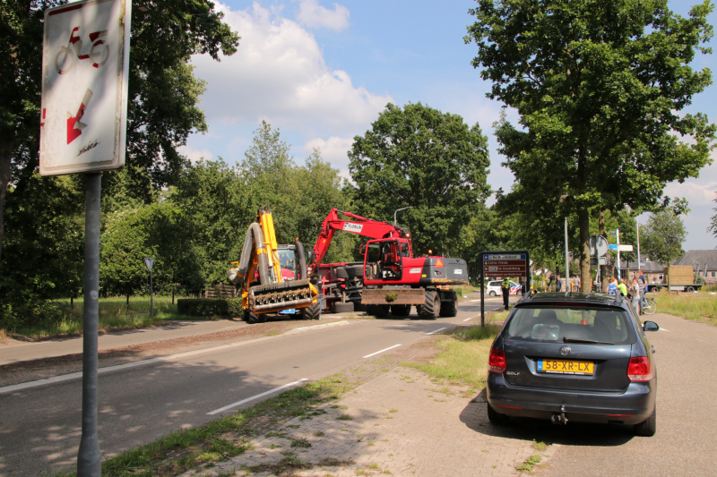 Kar met maai-afval achter trekker kantelt