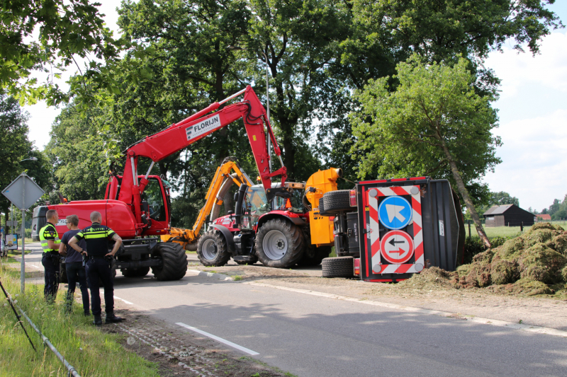 Kar met maai-afval achter trekker kantelt