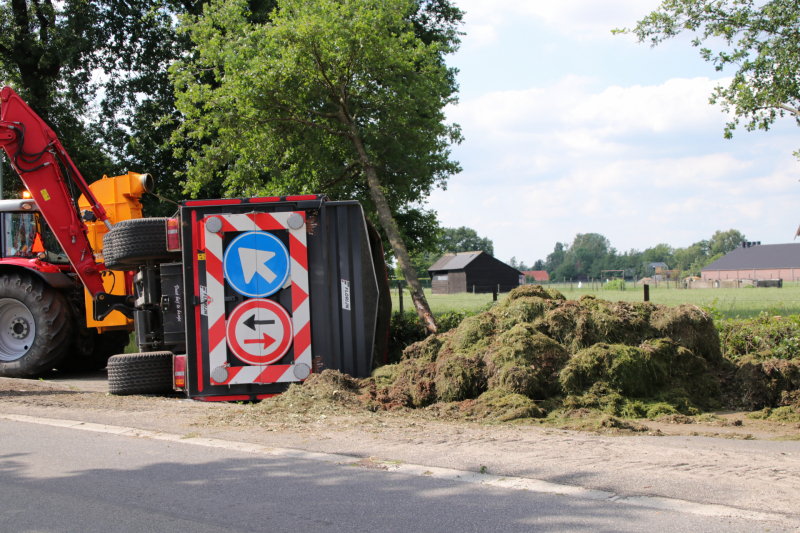 Kar met maai-afval achter trekker kantelt