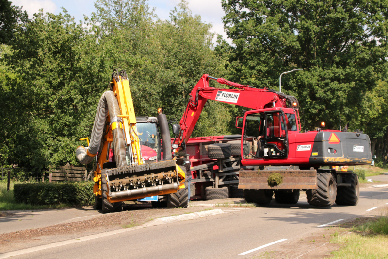 Kar met maai-afval achter trekker kantelt