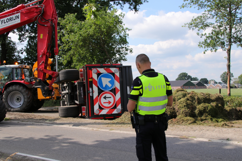 Kar met maai-afval achter trekker kantelt