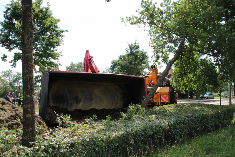 Kar met maai-afval achter trekker kantelt
