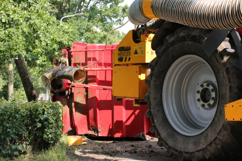 Kar met maai-afval achter trekker kantelt