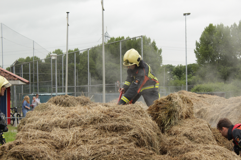 Brandweer blust smeulende hooibalen