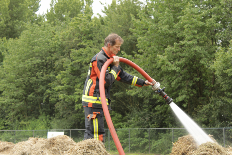 Brandweer blust smeulende hooibalen