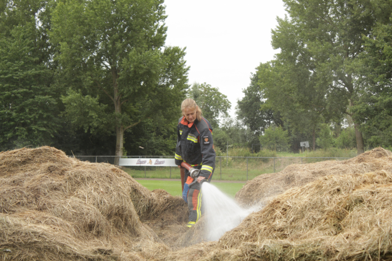 Brandweer blust smeulende hooibalen