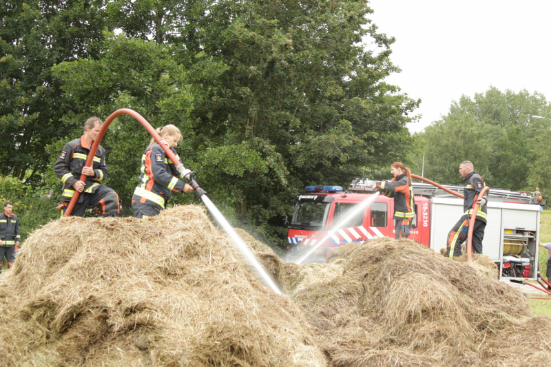 Brandweer blust smeulende hooibalen