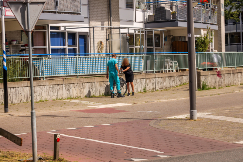 Vrouw met voet tussen spaken fiets