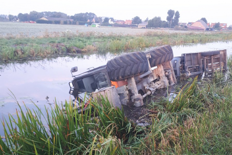 Graafmachine met aanhanger belandt te water