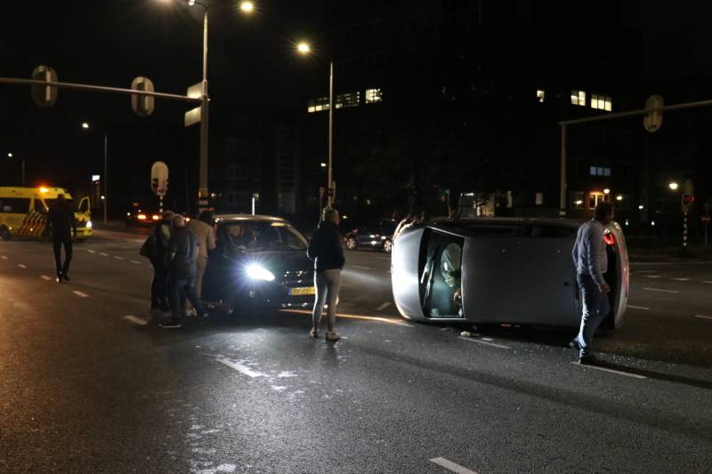 Auto belandt op zijkant na botsing; inzittende gewond bij reddingsactie