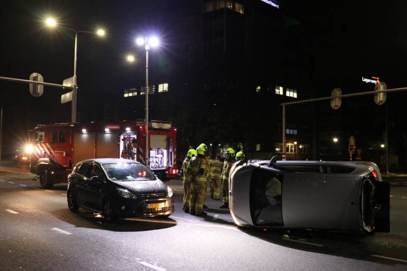 Auto belandt op zijkant na botsing; inzittende gewond bij reddingsactie