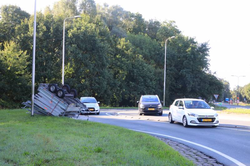 Aanhangwagen met steigerdelen kantelt