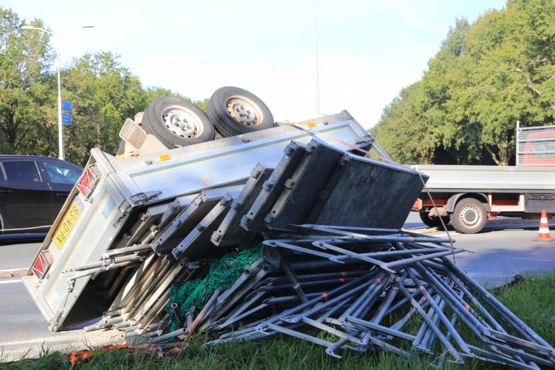 Aanhangwagen met steigerdelen kantelt