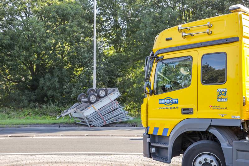 Aanhangwagen met steigerdelen kantelt