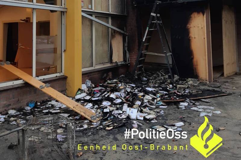 Winkelwagentje met oud papier en schoolboeken op schoolplein in brand gestoken