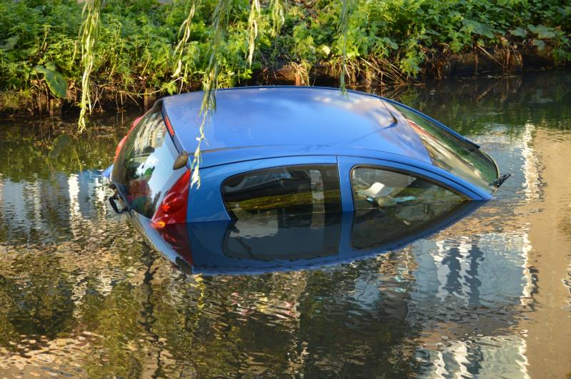 Automobilste rijdt met auto water in