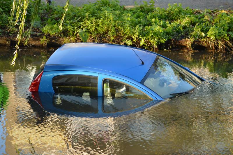 Automobilste rijdt met auto water in