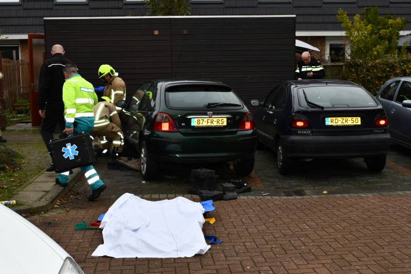 Persoon bekneld onder auto