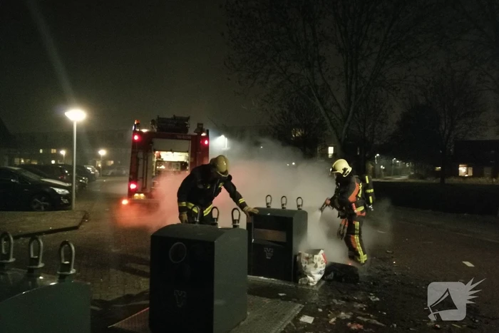 Vuurwerkresten in de brand naast papiercontainer