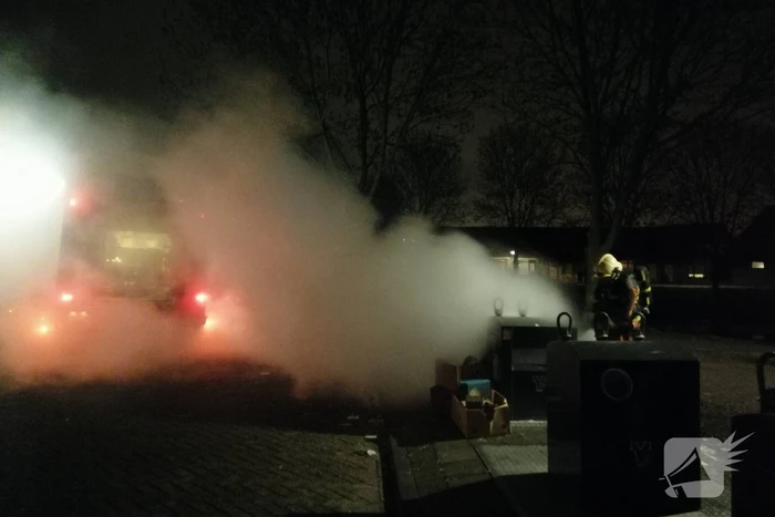 Vuurwerkresten in de brand naast papiercontainer