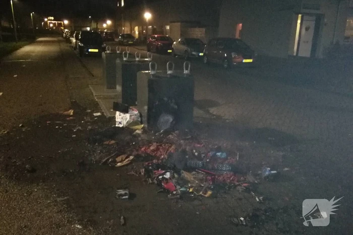 Vuurwerkresten in de brand naast papiercontainer