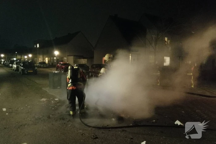 Vuurwerkresten in de brand naast papiercontainer