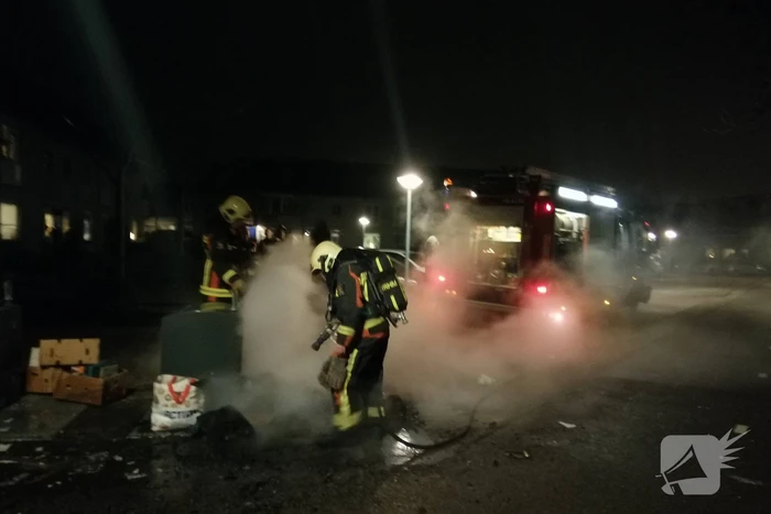 Vuurwerkresten in de brand naast papiercontainer