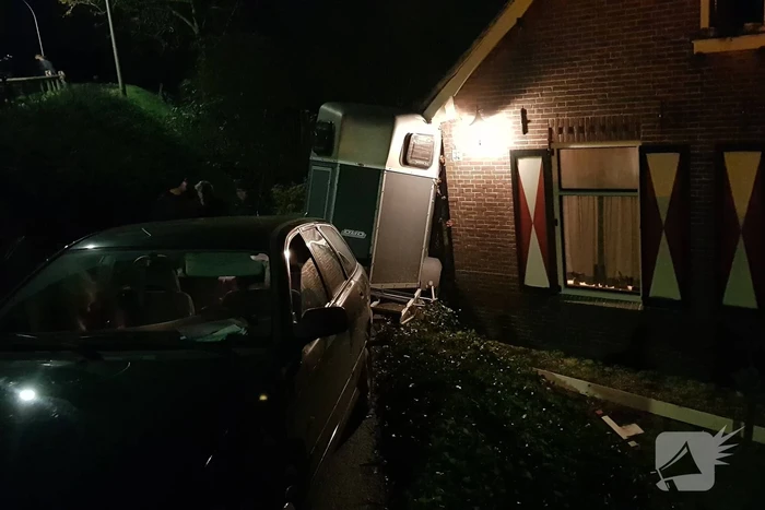 Auto met paardentrailer botst tegen huis.