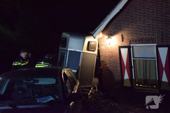 Auto met paardentrailer botst tegen huis.