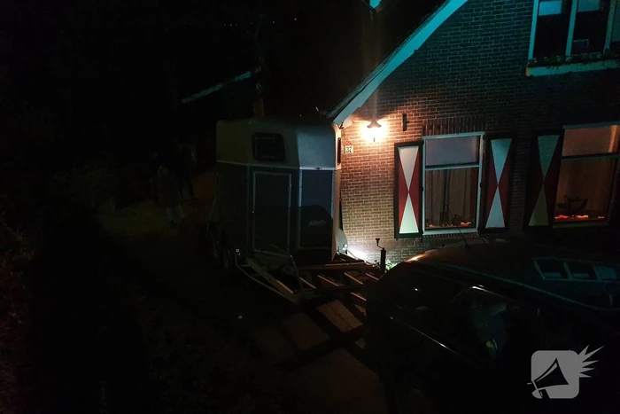 Auto met paardentrailer botst tegen huis.
