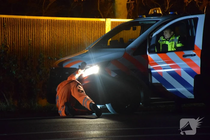 Politieauto en personenauto beschadigd door stenen op rijbaan