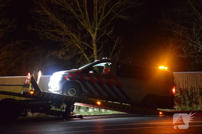 Politieauto en personenauto beschadigd door stenen op rijbaan