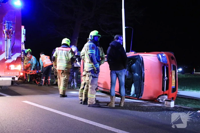 Auto op zijn kant na botsing tegen lantarenpaal