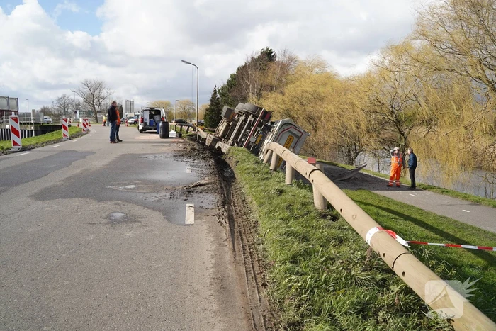 Vrachtwagen met zand van dijk gekanteld
