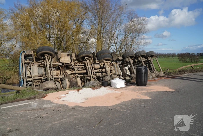 Vrachtwagen met zand van dijk gekanteld