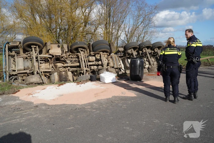 Vrachtwagen met zand van dijk gekanteld