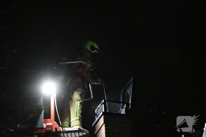 Vlammen slaan uit schoorsteen van woning