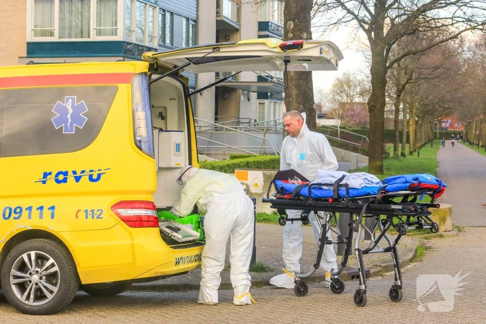 Mannen in witte pakken halen vermoedelijke coronapatiënt uit huis