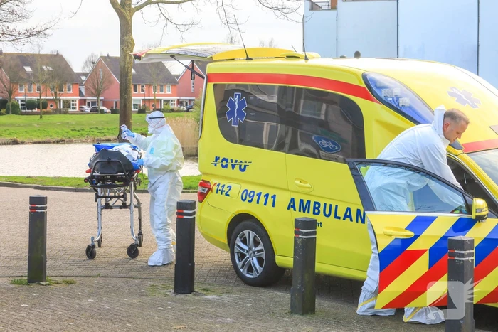 Mannen in witte pakken halen vermoedelijke coronapatiënt uit huis