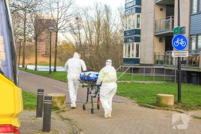 Mannen in witte pakken halen vermoedelijke coronapatiënt uit huis