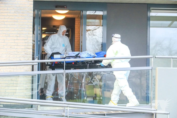 Mannen in witte pakken halen vermoedelijke coronapatiënt uit huis