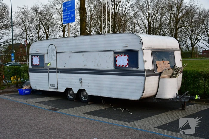 Handhaving sleept caravan met protesttekst weg van parkeerterrein gemeentewerf