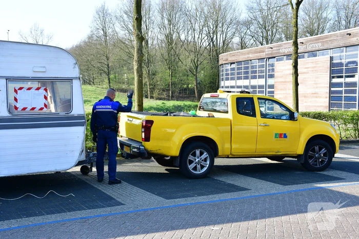 Handhaving sleept caravan met protesttekst weg van parkeerterrein gemeentewerf