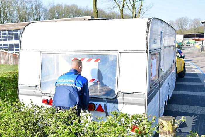 Handhaving sleept caravan met protesttekst weg van parkeerterrein gemeentewerf