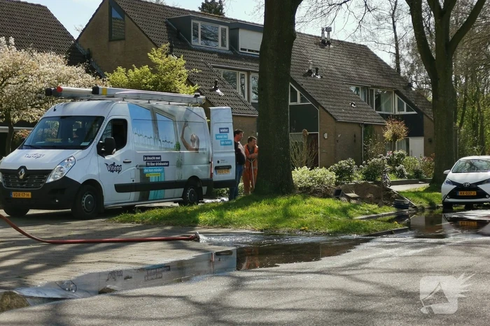 Water stroomt de weg op na leidingbreuk