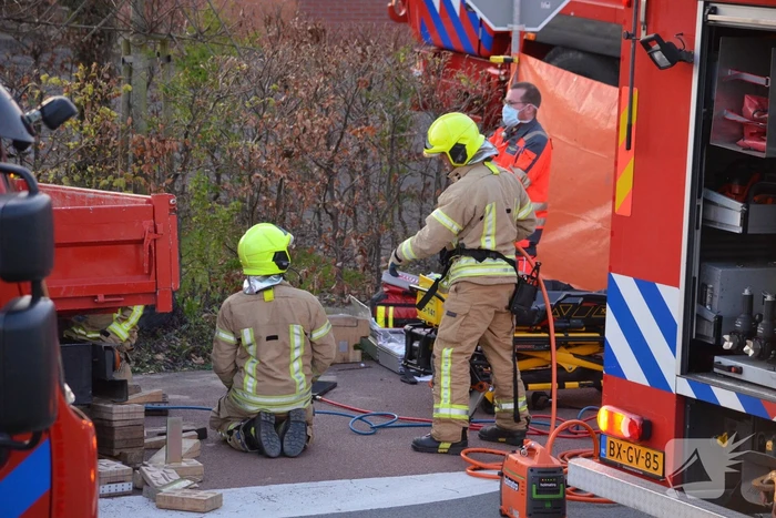 Man bekneld onder as van bedrijfswagen