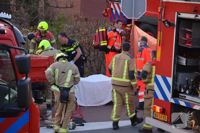 Man bekneld onder as van bedrijfswagen