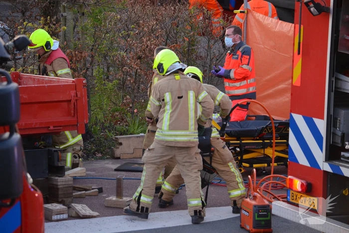 Man bekneld onder as van bedrijfswagen
