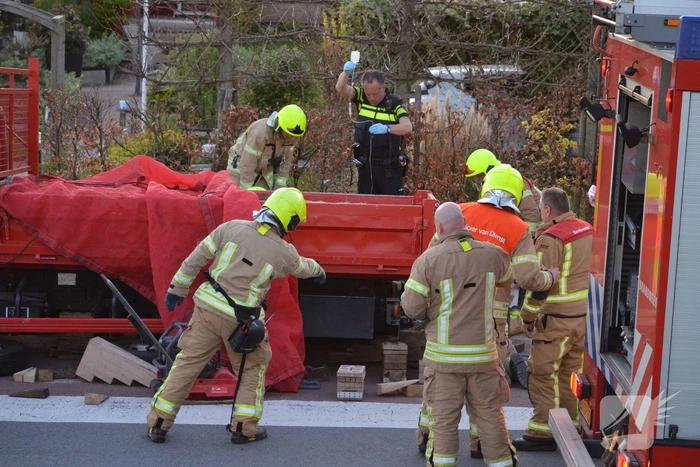 Man bekneld onder as van bedrijfswagen