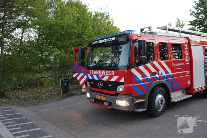 Omstanders doven vuur in prullenbak op parkeerterrein